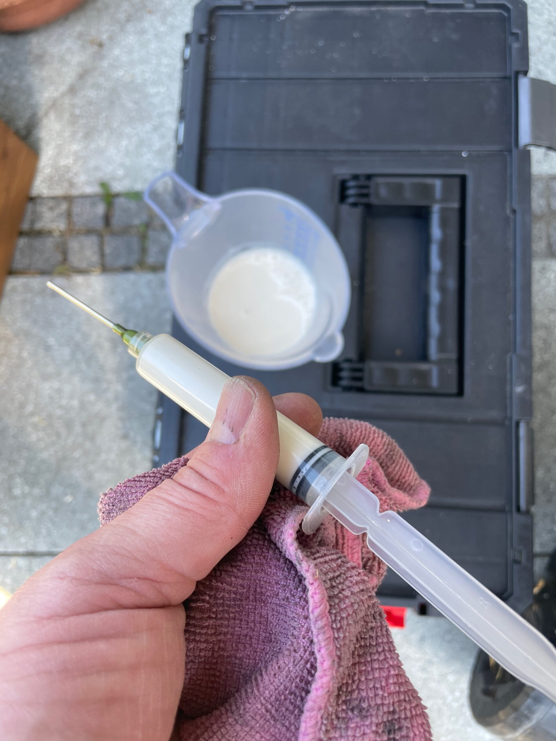 Dichtmilch wird aus einem Messbecher in eine Spritze aufgezogen
